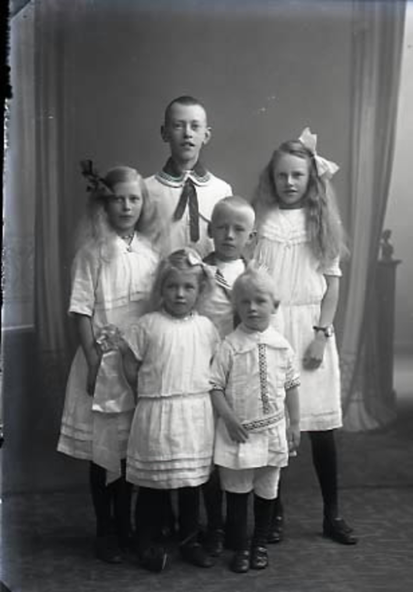 Syskongrupp, sex (6) barn i olika åldrar stående i helfigur.  Ateljébild.