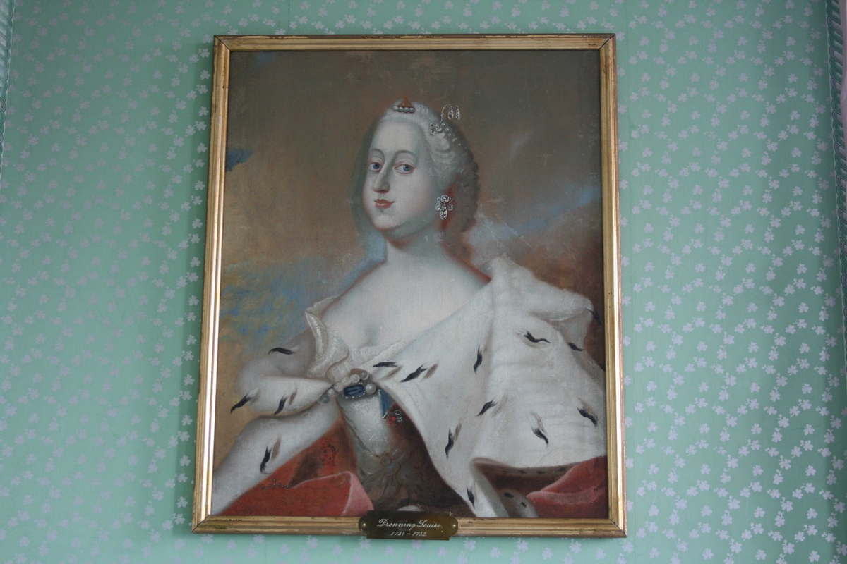 Dronning Louise 1724 - 1752. Portrett i halvfigur. Kvinne med parykk, rød kappe med hermelin. Rokokkokjole. Smykker m/perler og juveler, i håret og på drakt. 
Bakgrunn blågrå, gylden.