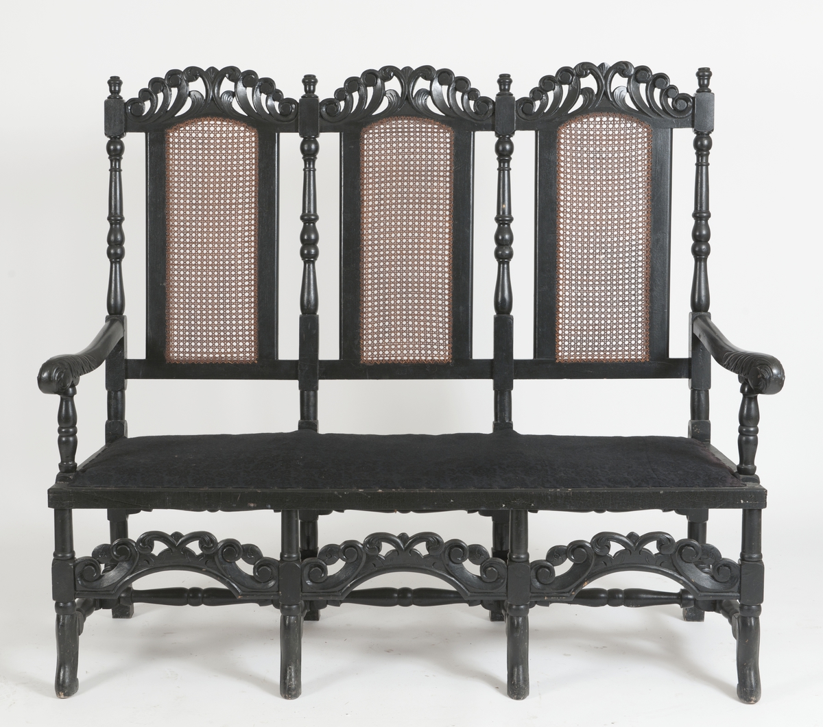 Sortmalt kanapé med trekk i sort, åtte stk ben og spross. Rygg av rotting. Skåret og dreid ornamentikk.