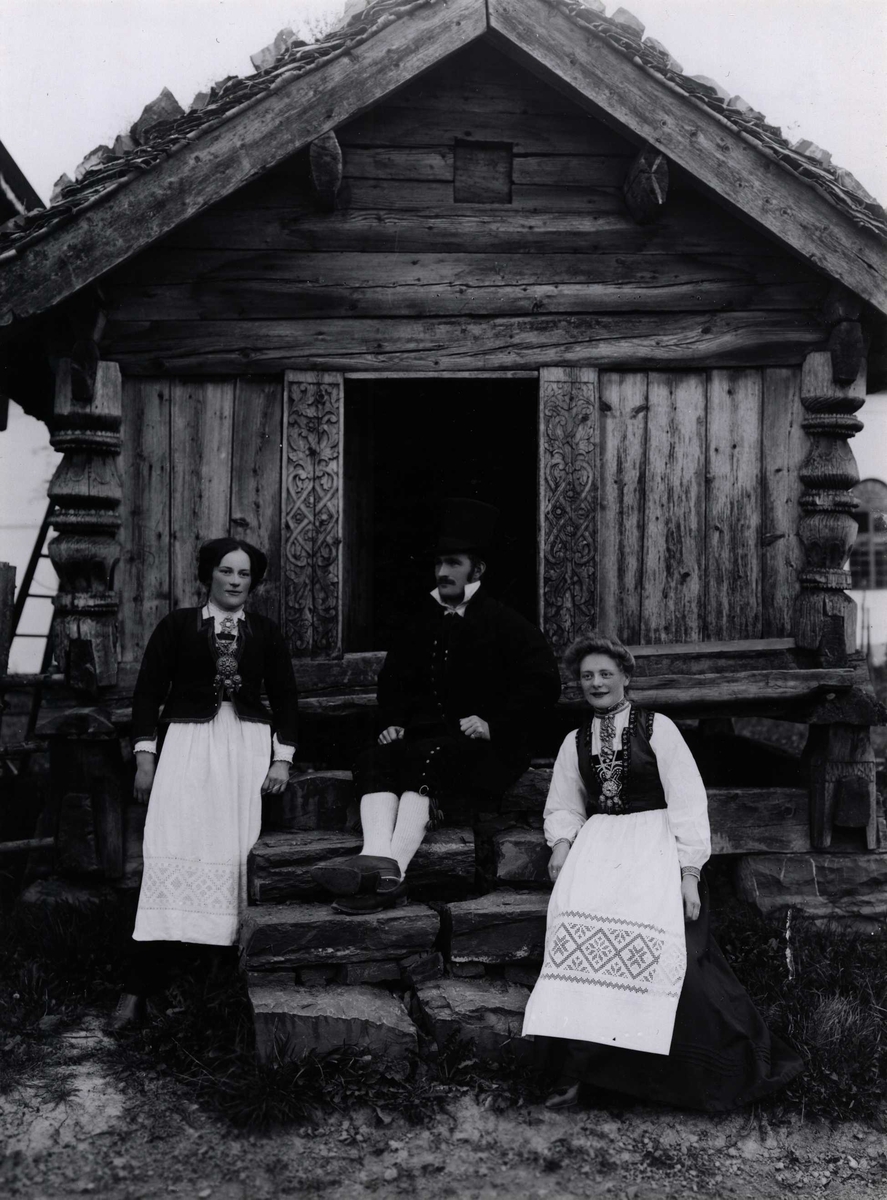 Tunverter i drakter foran bur fra Rofshus ved Telemarkstunet på Norsk Folkemuseum, antagelig 1903.