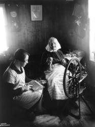 To kvinner sitter i en stue og karder og spinner, 1929.