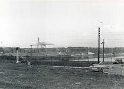 En mann sitter ved et jernbanespor. I bakgrunnen lagres tømm