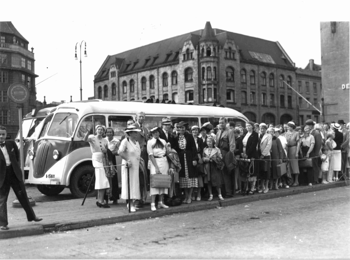 Friluftsliv. Jernbanetorget, Oslo. 1937. Kø for buss til Ingierstrand. Sommerkledde barn, kvinner og menn.