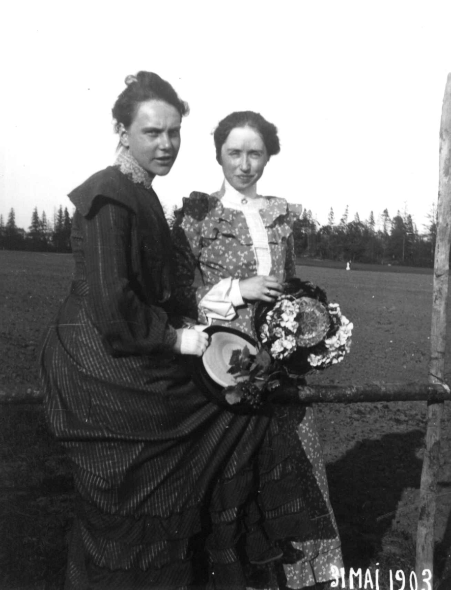 To kvinner utendørs, ukjent sted, 31.mai 1903. Begge holder hatter i hendene.