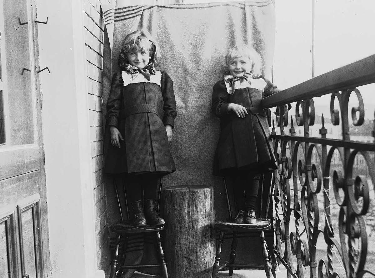 Gudrun og Karen Q. Wiborg fotografert på balkong, ant Meltzers gate 9, Oslo, 1899, mot opphengt bakteppe. 