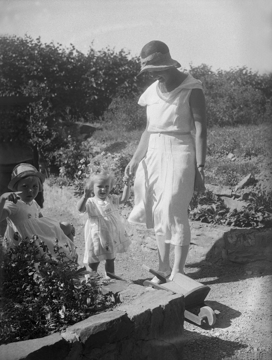 Søstrene Siri og Guri står i hagen sammen med sin mor Dordi Arentz. Fotografert 1932.