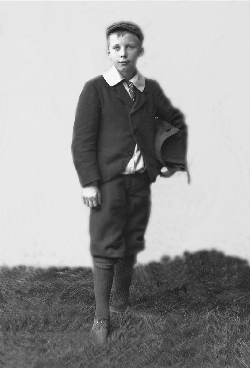 Portrett, gutt med yttertøy, knebukser, sixpence og veske. Harald Borchgrewink.