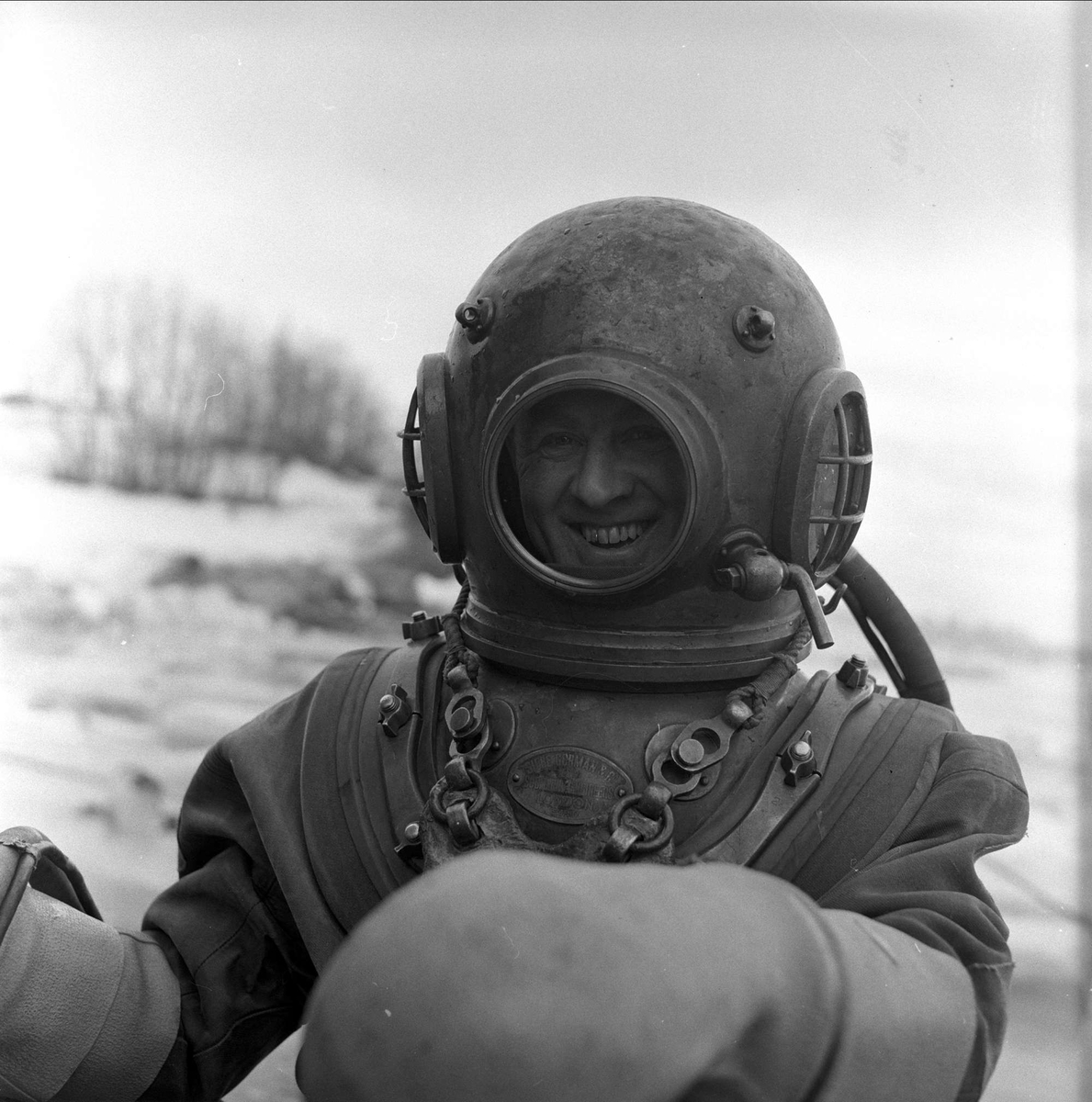 Trelleborg Gummi legger ut slange ved Sarpsborg, mars, 1959. Mann i dykkerdrakt.