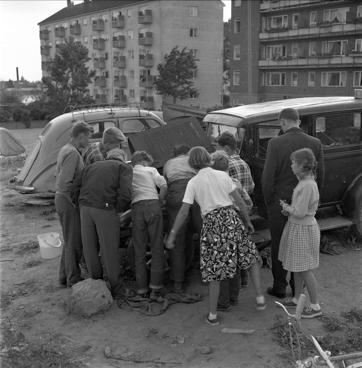 Mennesker og biler foran boligblokker, Hamar, juli.1959.