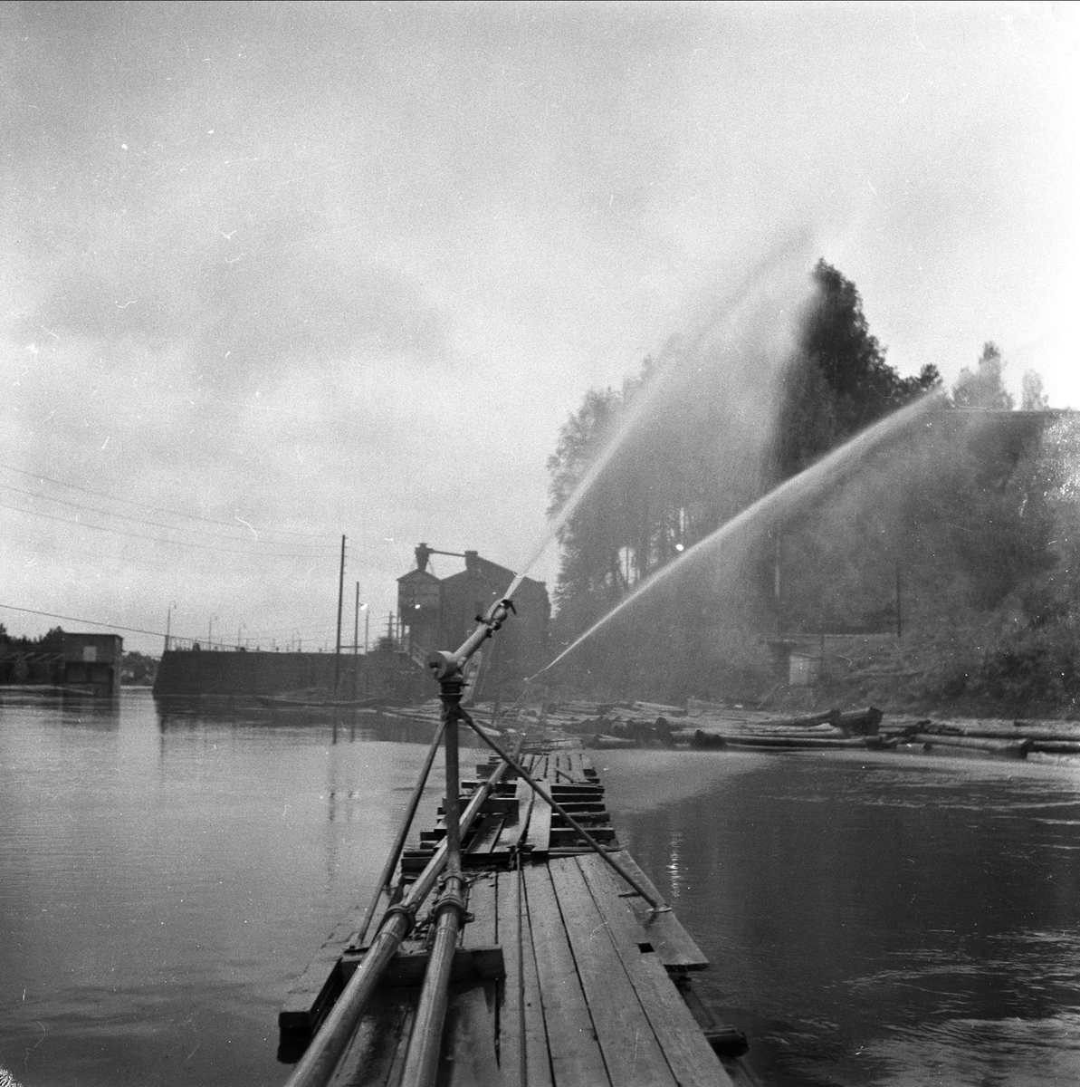 Holmen Brug i Hokksund, Øvre Eiker, Buskerud, 02.10.1958. Vannspreder til tømmer på elv.