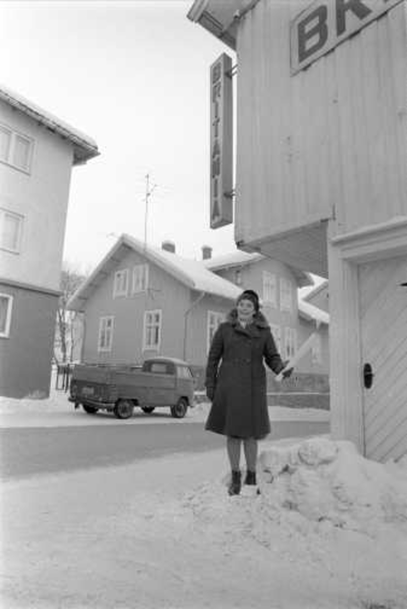 Drøbak, Frogn, 01.03.1970. Kvinne i bygate med snø. Trehusbebyggelse.