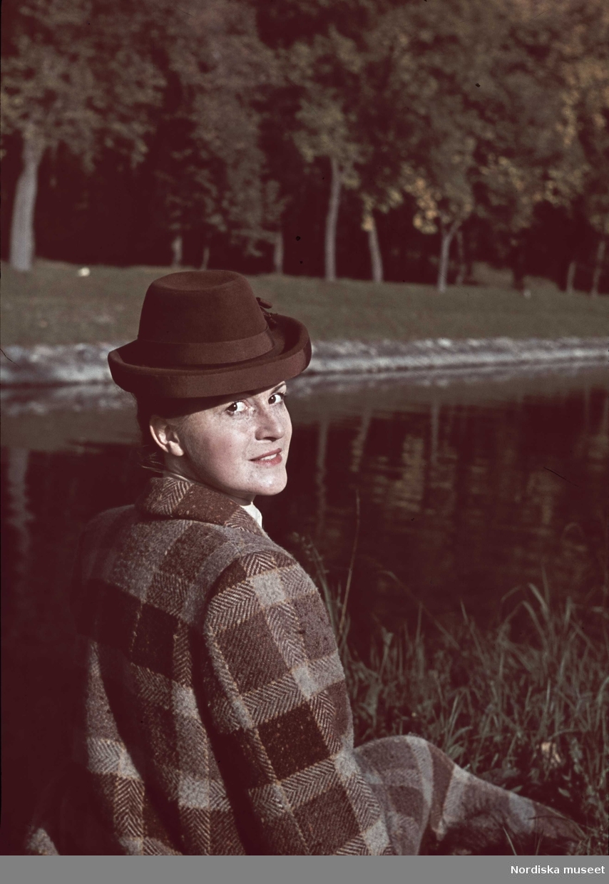 Kvinna i rutig tweedkappa och brun hatt.