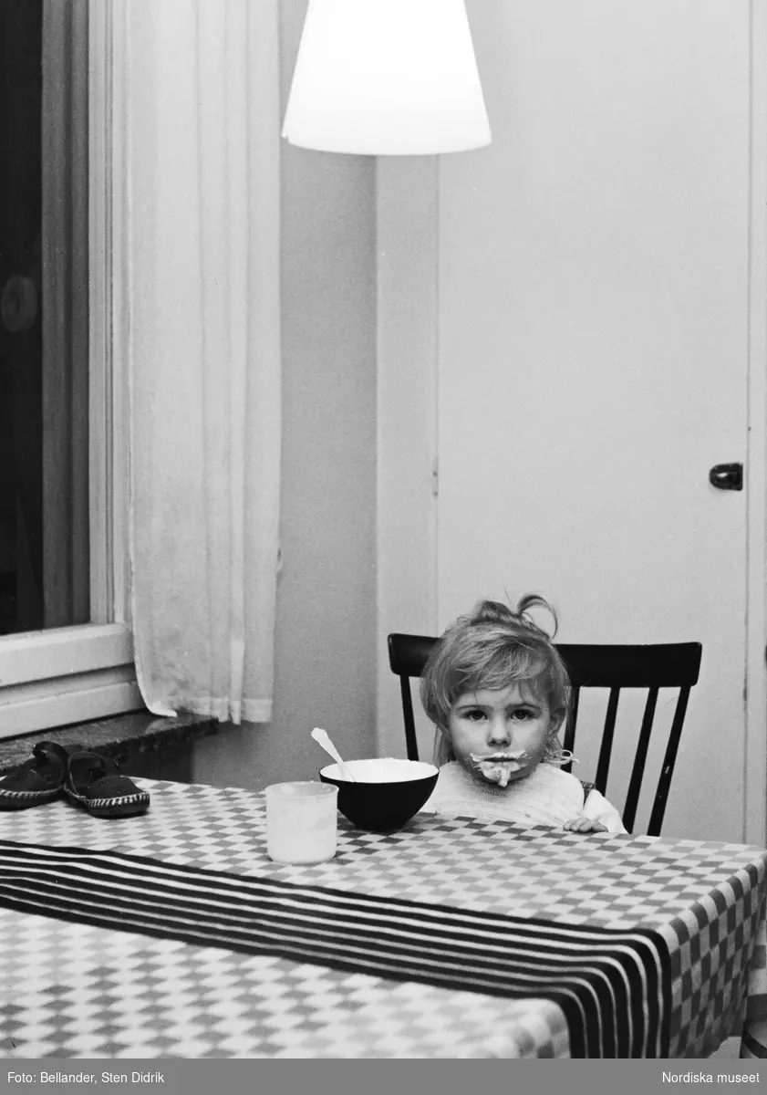 Fotografens dotter Tove äter vid köksbordet.