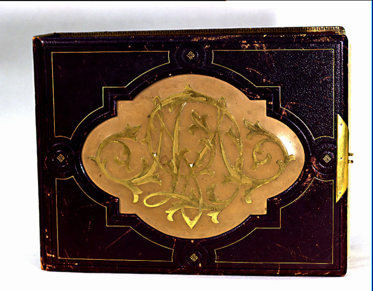 Fotoalbum av mörkbrunt läder med spänne av metall. Stort monogram "MD" i gulmetall innefattad i spegel av ljusbrunt skinn på framsidans pärm. På försättsbladet är en akvarell signerad "H. Schmidt." målad. Akvarellen går i färgerna grönt, rosa och guld och den ramar in texten "BAGARMÄSTAREN MATTHIAS DÜBOIS DEN 30 JULI 1892 AF VÄNNER". Albumet innehåller porträttfotografier (förmodligen Matthias Dubois samt vänner och kollegor till honom) samt kända vyer från Uppsala.