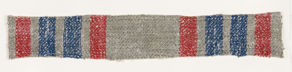 Vävprov ämnat för bolstervarstyg vävt med bomulls- och lingarn, kypert. Randigt i rött, blått och grått. Vävprovet är uppklistrat på en kartong i storleken 22 x 28 cm. I övre högra hörnet finns en stämpel "Uppsala läns hemslöjdsförening" och ett handskrivet nummer, "A.1624".