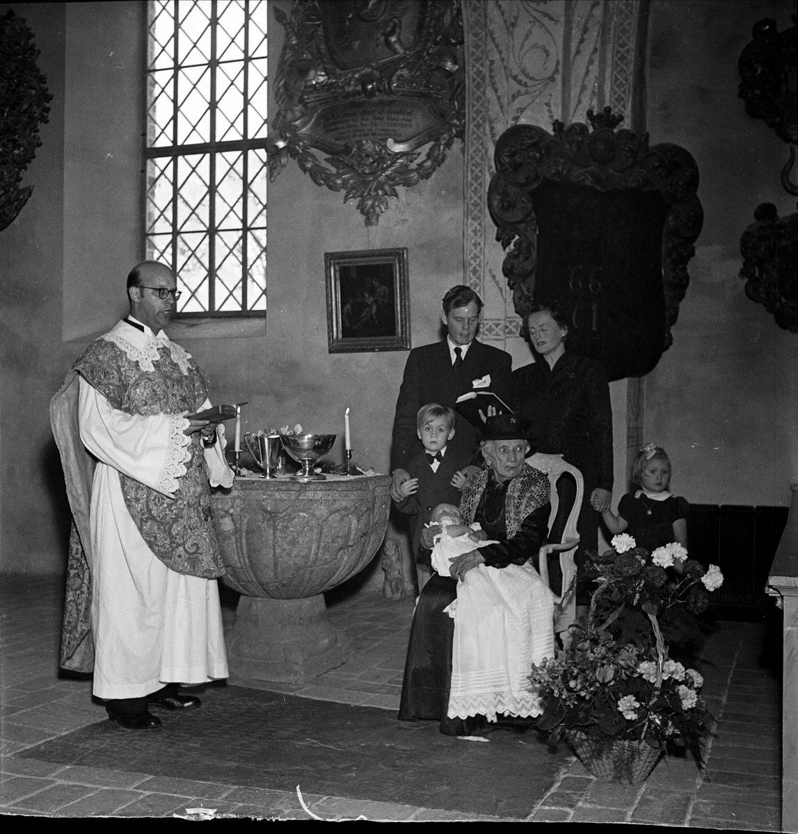 Dop - 100-årig kvinna bär fram sonsonson i Håtuna kyrka, Håtuna socken, Uppland 1954