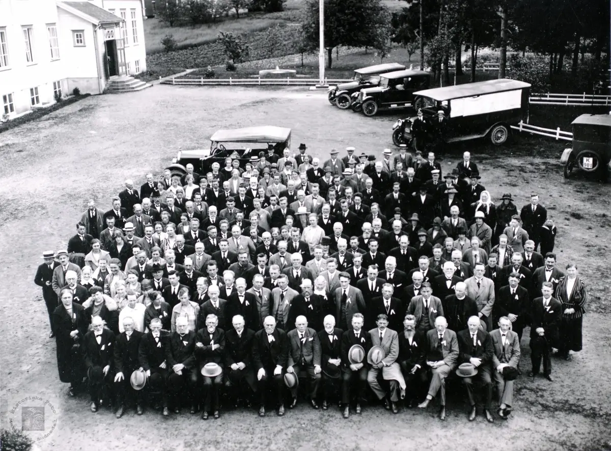 Portrett av stor gruppe med kjøretøy fra 1920 tallet i bakgrunnen.