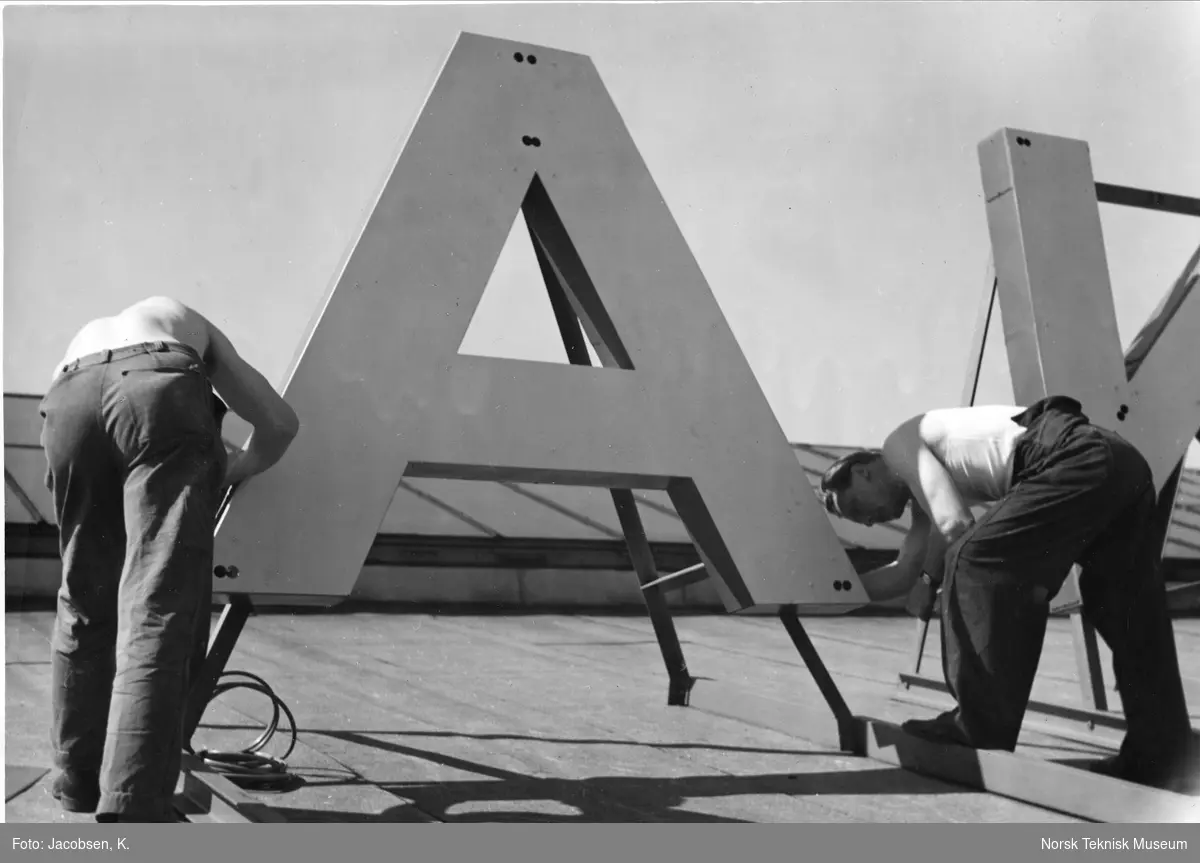 Montering av lysreklame på taket av dieselmotorverkstedet til Akers mek. Verksted, Pipervika omkring 1950. 