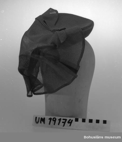 471 Tillverkningstid 1940-TAL
394 Landskap BOHUSLÄN

Liten vinröd hatt i glesvävt tyg med löst tygstycke fastsatt bak med rosett och nackband.