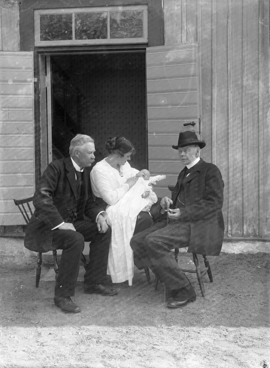 En kvinna med ett barn (dopklädsel?) samt två män, troligen 16 maj 1918