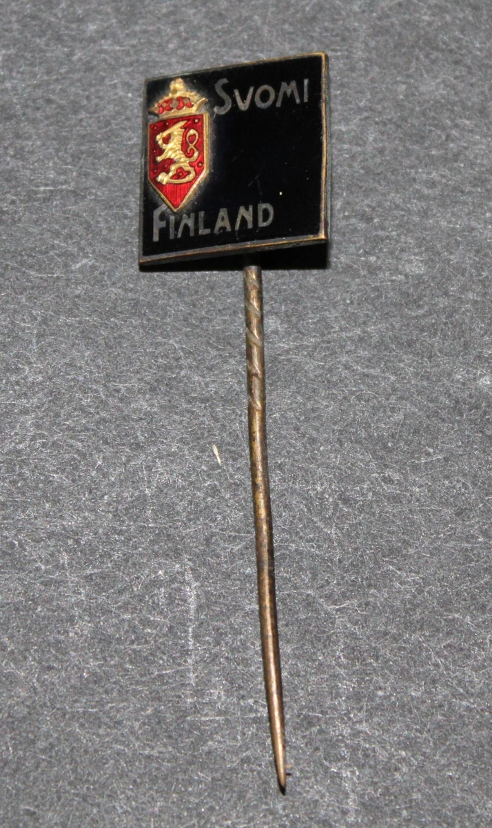 Rockslagsnål, fyrkantig med svart emaljplatta med finska riksvapnet i rött och texten: Suomi Finland i vitt.