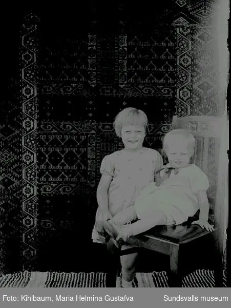 Porträtt. Två barn på en stol.