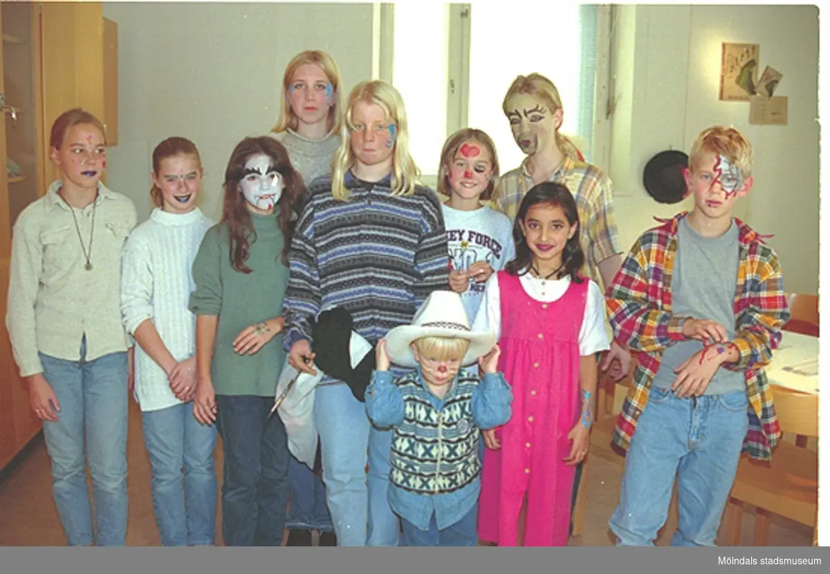 Sminkade barn som står uppställda framför kameran. Det har varit sminkverkstad för hela familjen. Familjesöndag på Mölndals Museum den 8/10 1995 under utställningen "Krinoliner och kortkort".