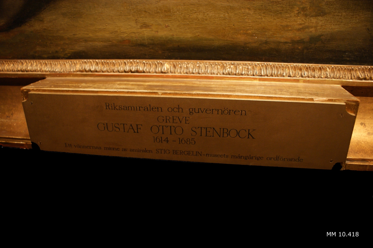 Oljemålning på duk monterad i ram föreställande riksamiral Gustaf Otto Stenbock (1614-1685). Mansperson med mörkt hår i barockfrisyr med mittbena, lockigt och axellångt. Ansad mustasch och litet hakskägg. Iklädd harnesk och blå mantel. Skärp av guldbroderad brokad, ljusbruna, vid byxor (eller benskydd) till knäna. Stövlar (eller skor med mörka strumpor) försedda med spännen, svagt rundad tåhätta och klack. Under harnesk skymtar dräkt med gula ärmar, med vit kant närmast handleden.
Mannen håller vad som troligen en tubkikare i höger hand och i vänster hand skymtar en värja fösedd med vad som ser ut att vara ett förgyllt lejonhuvud.
Mannen står framför en byggnad med en murad vägg på vänster sida och en balustrad på höger sida. På marken små grästuvor. I bakgrunden bladverk och bakom detta reser sig masterna av ett eller flera svenska örlogsfartyg, med flaggor och vimplar hissade.
Ingen signatur syns i bildytan.
Målningen är utförd med mörka färgtoner, ljusdunkel, detaljer främst i mannens ansikte. Fernissad duk.
Profilerad ram av förgyllt trä, B = 180mm, med ornering av förgylld gips. Nederst fyrkantig platta, fastskruvad och försedd med text: "Riksamiralen och guvenören GREVE GUSTAF OTTO STENBOCK 1614-1685. Ett vännernas minne av amiralen STIG BERGELIN - museets mångårige ordförande"