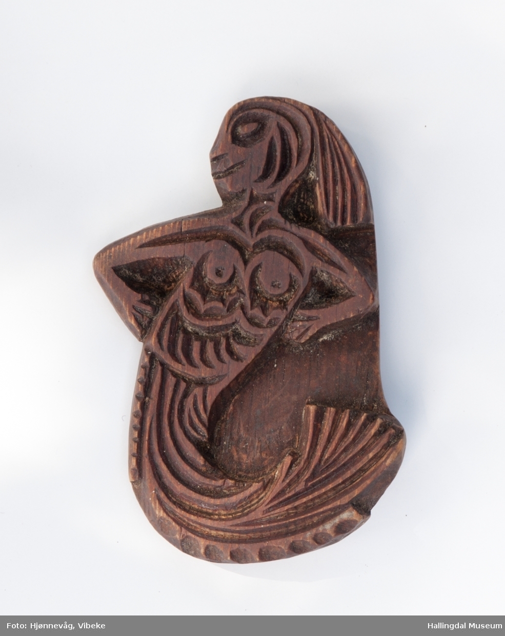 Relieff med motiv av en havfrue med hendene i siden. Håndtak på baksiden.