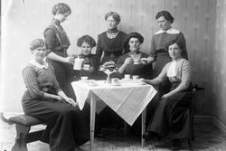 Gruppeportrett av kvinner rundt et kaffebord.