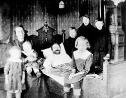 Tæringsyk familefar i sengen med familien rundt seg, ca. 192