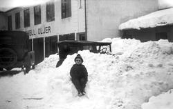 Gutt i snøen i bakgård til bilforretningen Iversen og Braate