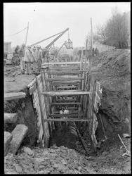 Graving av dyp grøft med forskaling, rør i bunnen, kjerre, h