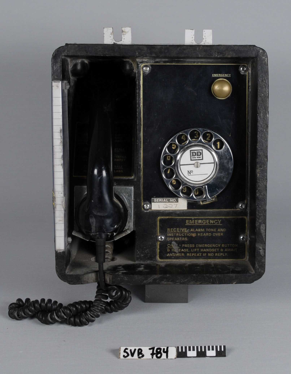 Telefonapparat til å henge på veggen. Bygget inn i en sort kasse. Dreieskive med nummer