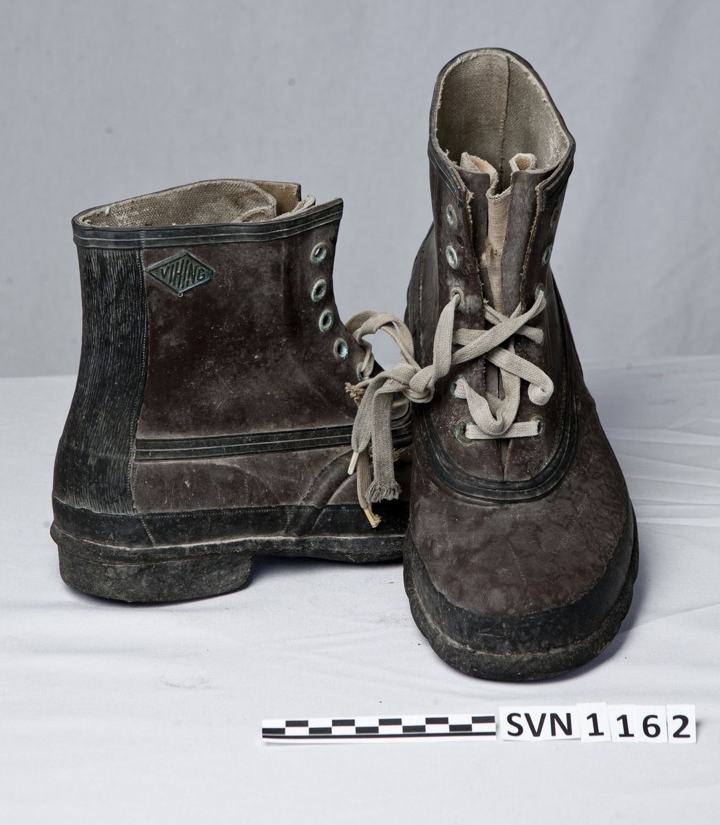Et par brune gummistøvler med hvite lisser. Svarte såler. Tekstil på innsiden.