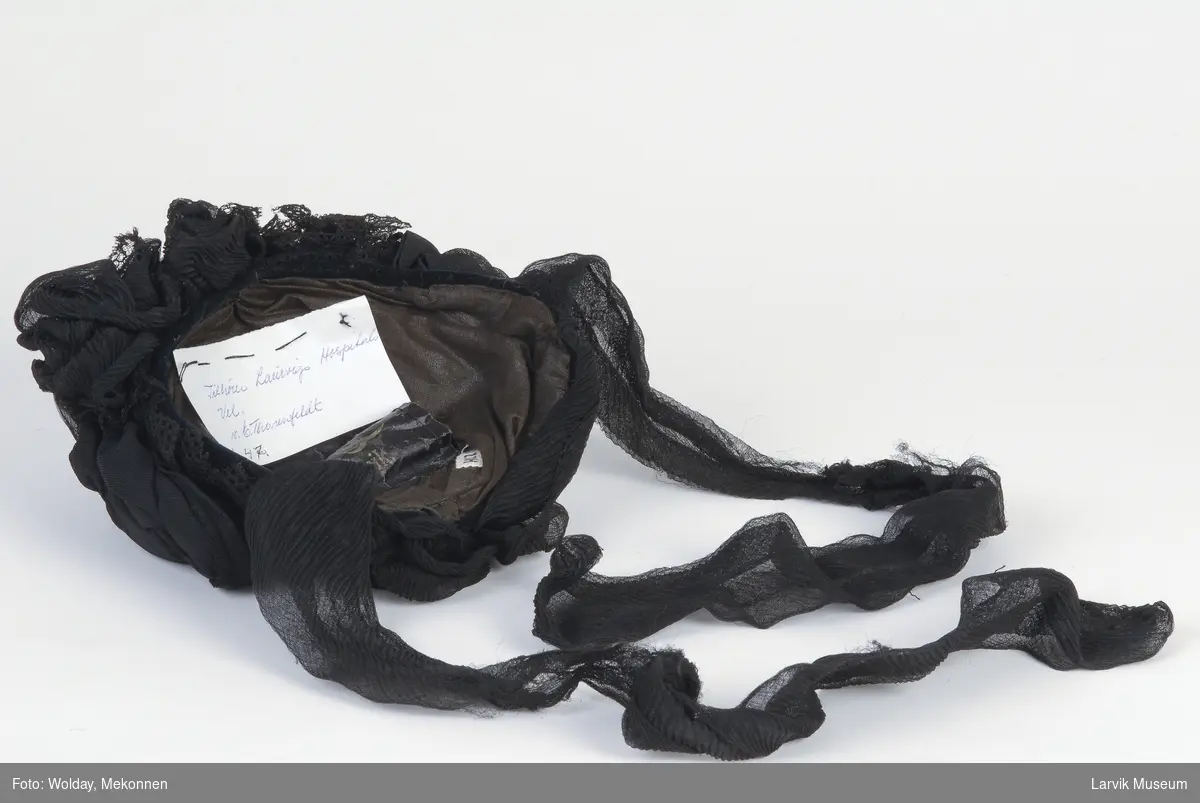 Form: draperinger av sort silkejersey og sort maskin-

