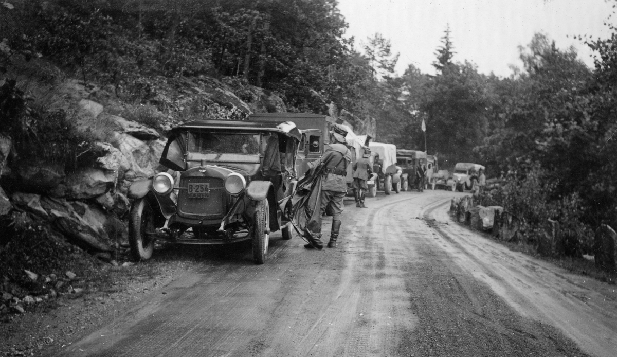 Årøsvingen i øsregn. 1937. Lastbiler og soldater kjører  videre.