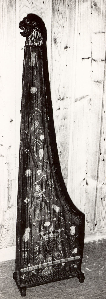 Toppstykket form av et utskåret løvehode. Malt dekorasjon ( blomster, fugl, harpespiller)