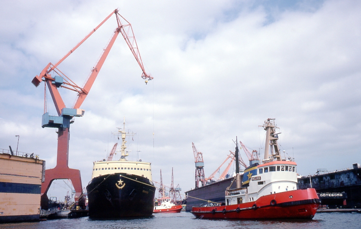 Fartyg: HELIOS                        Bredd över allt 9,48 meterLängd över allt 32,60 meterReg. Nr.: 7321659Byggår: 1973Varv: Åsiverken, ÅmålÖvrigt: Denna bild är tagen under en rundtur med någon av PADDAN-båtarna i Göteborgs hamn, ovisst exakt var: LENINGRAD, sovjetiskt fartyg t v som inte kunnat identifieras närmare (flera fartyg har burit detta namn) bogseras av bogseraren HELIOS, ex VICTORIA, senare ARCTIC HELIOS. Vem som ägde HELIOS vid fotograferingstillfället har inte gått att fastställa.