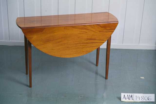 Klaffebord, av mahogny,  polert.  Bredt klaffebord med rundede klaffer.  En skuff med messingknott i hver ende. Rette ben.