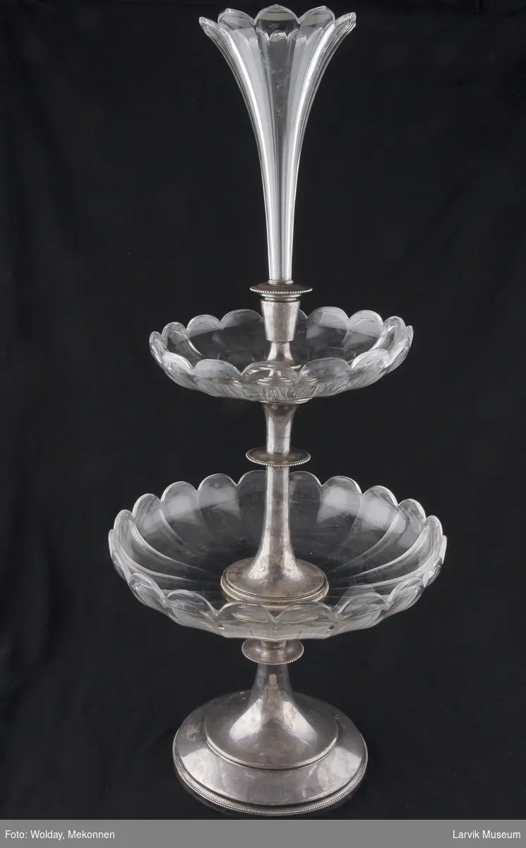 Teknikk: fot og stangholder av forsølvet hvitmetall- legering, vase og 2 skål/fat av slepent krystall, vasen er avtagbar
Form: rund, slank
