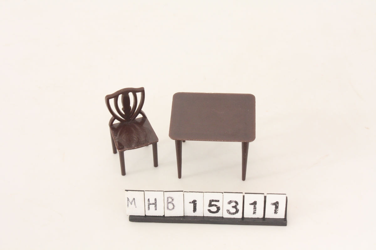 Møbel til dukkehus. En stol og et bord i brun plast.