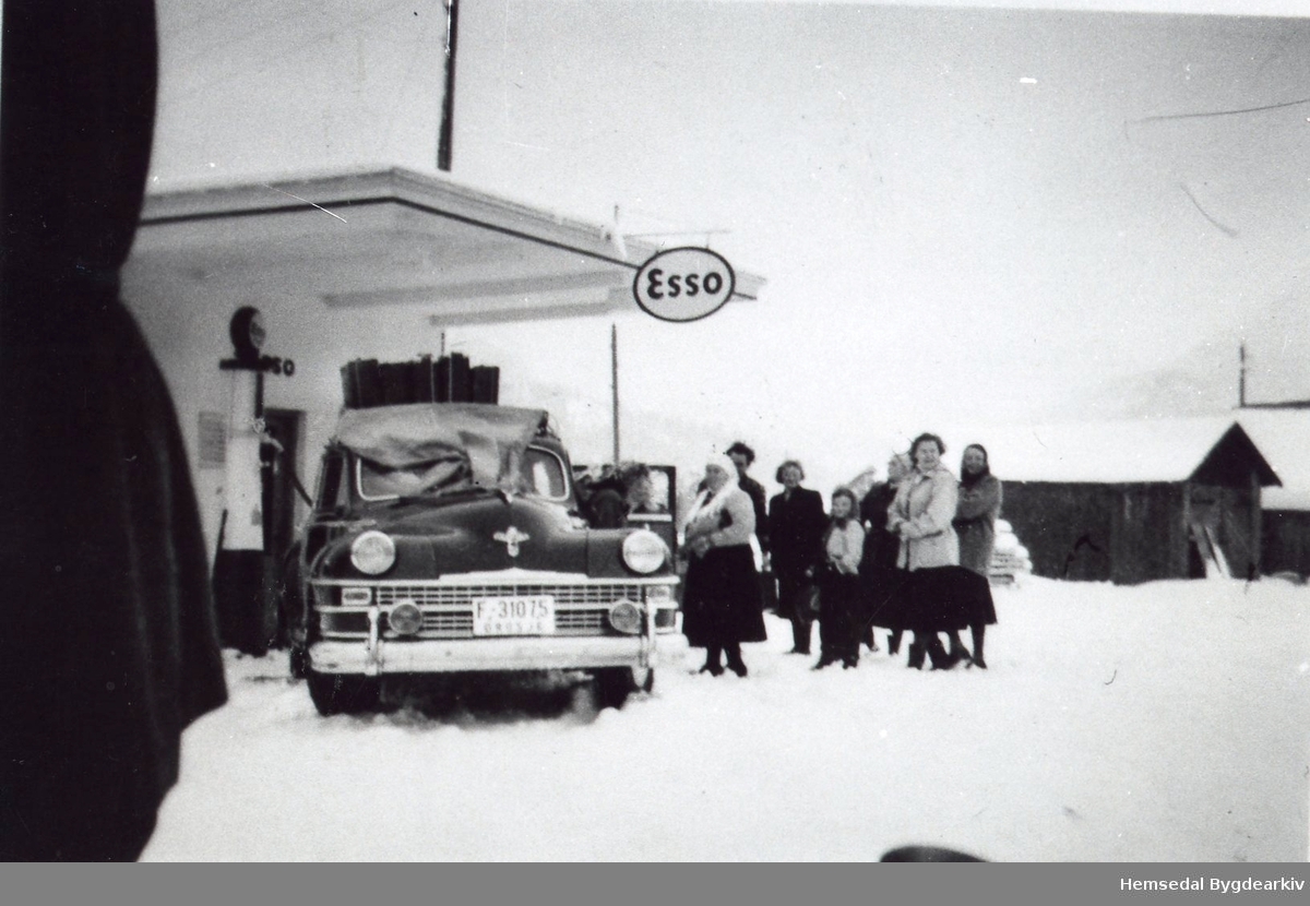 Drosje F-31075 , De Soto, til Mekkel Ødegård ved bensinstasjonen ved Tuv samvirkelag.
Frå venstre: Maria Fekene, jenta i midten er Ingebjørg Helgesen. Til høgre: Birgit Fekene.