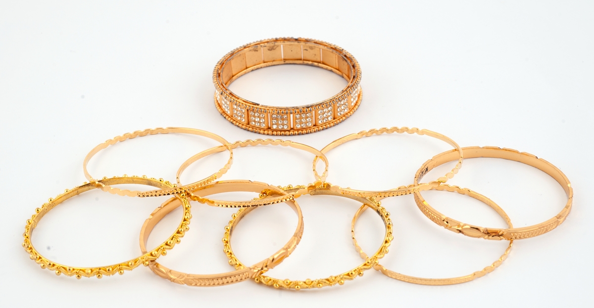 Gullfargede smykker til brudedrakt. Består av 9 armringer, et par øreheng, 2 halssmykker og 2 anheng = ukjent bruk