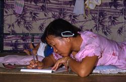 Kvinne skriver, - i Tuen Mun flyktningeleir i Hong Kong.