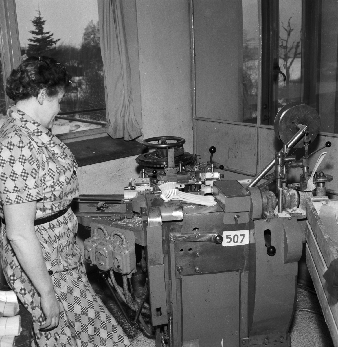 En kvinna arbetar vid en maskin för tillverkning av diskborstar på Huskvarna Borstfabrik.