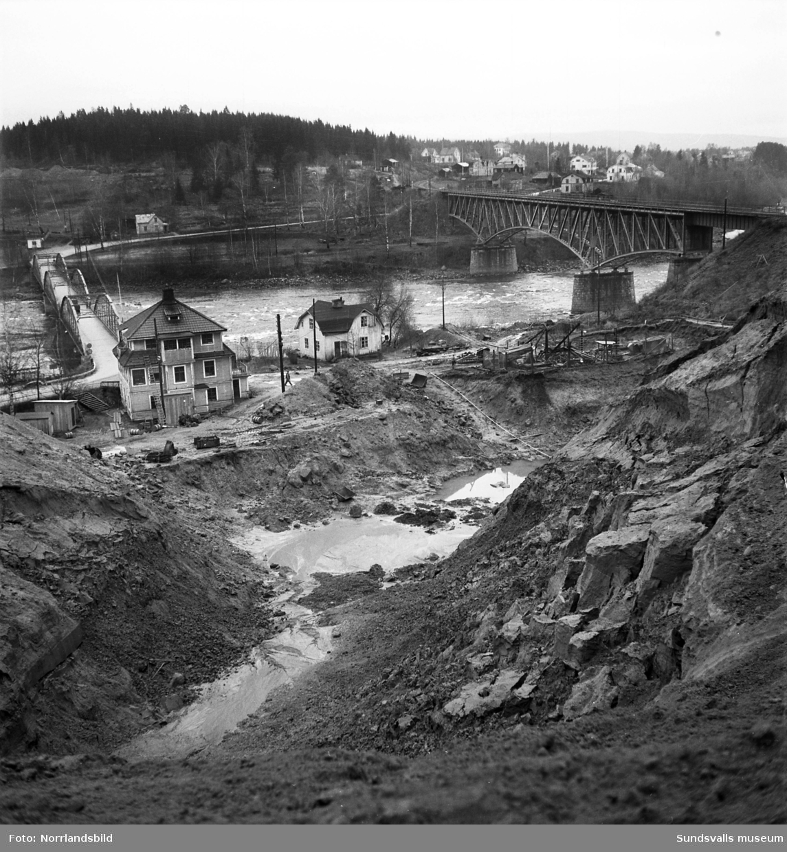 I Bergeforsen har grävningsarbetena inför bygget av kraftverket börjat. På bilderna syns järnvägsbron, gamla landsvägsbron samt byggnader på områden som numera är uppdämda.