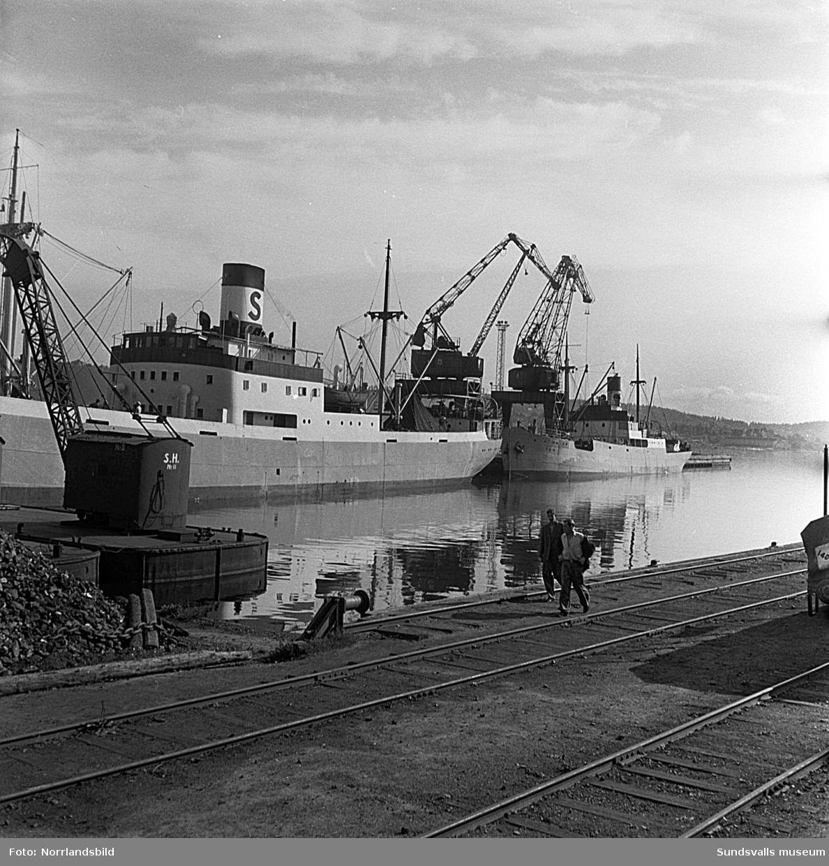 En serie bilder från verksamheten i hamnen i början av 1950-talet. Båtar, pråmar, kranar, kolhögar och magasin.