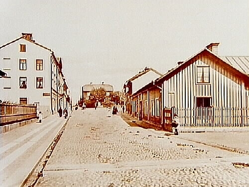 Storgatan norrut från Grev Rosengatan. En, två och tre vånings bostadshus.
Huset i mitten på bilden, Kolumbus hus, kallades även för "Blåsut".
Reproduktion efter en bild från 1903.