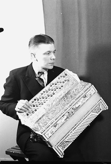 En man med musikinstrument (dragspel).
Knut Gustavsson